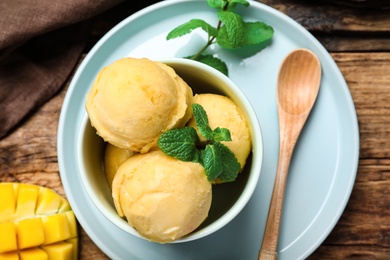 Photo of Delicious mango ice cream served on wooden table, flat lay