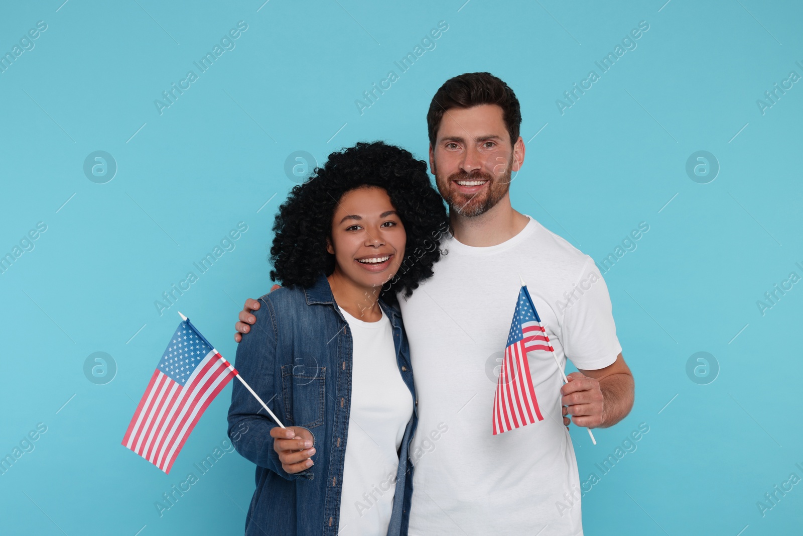 Photo of 4th of July - Independence Day of USA. Happy couple with American flags on light blue background