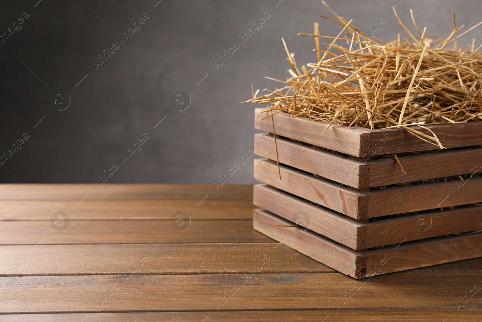 Photo of Dried straw in crate on wooden table, space for text