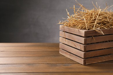 Dried straw in crate on wooden table, space for text