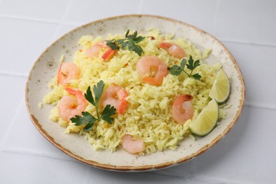 Photo of Delicious risotto with shrimps, lime and parsley on white tiled table, closeup