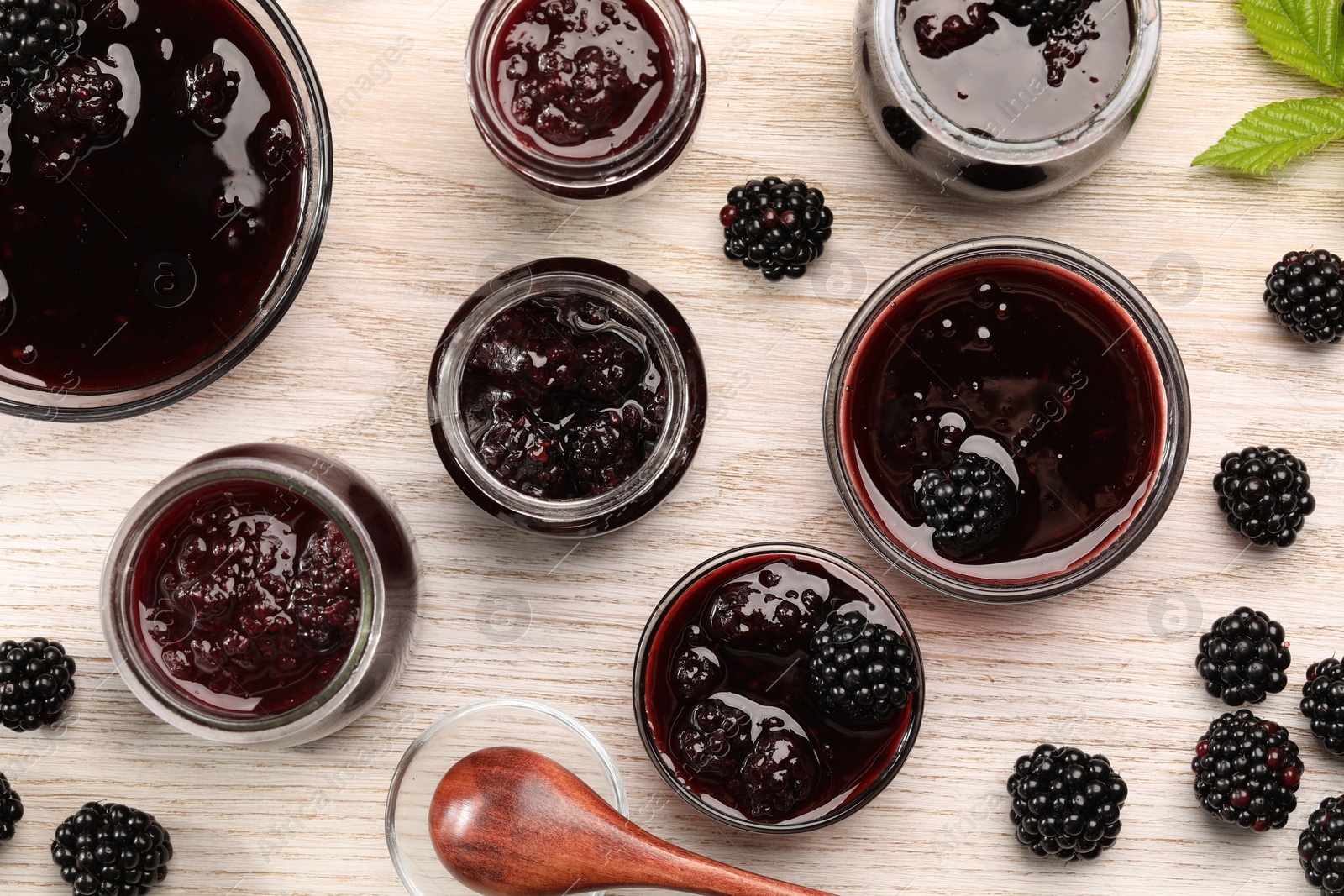 Photo of Tasty blackberry jam and fresh berries on white wooden table, flat lay