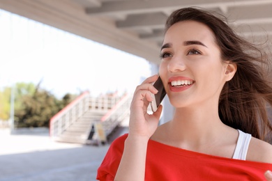 Photo of Young woman talking on mobile phone outdoors