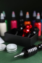 Photo of Tattoo machine and tools on dark green table, closeup