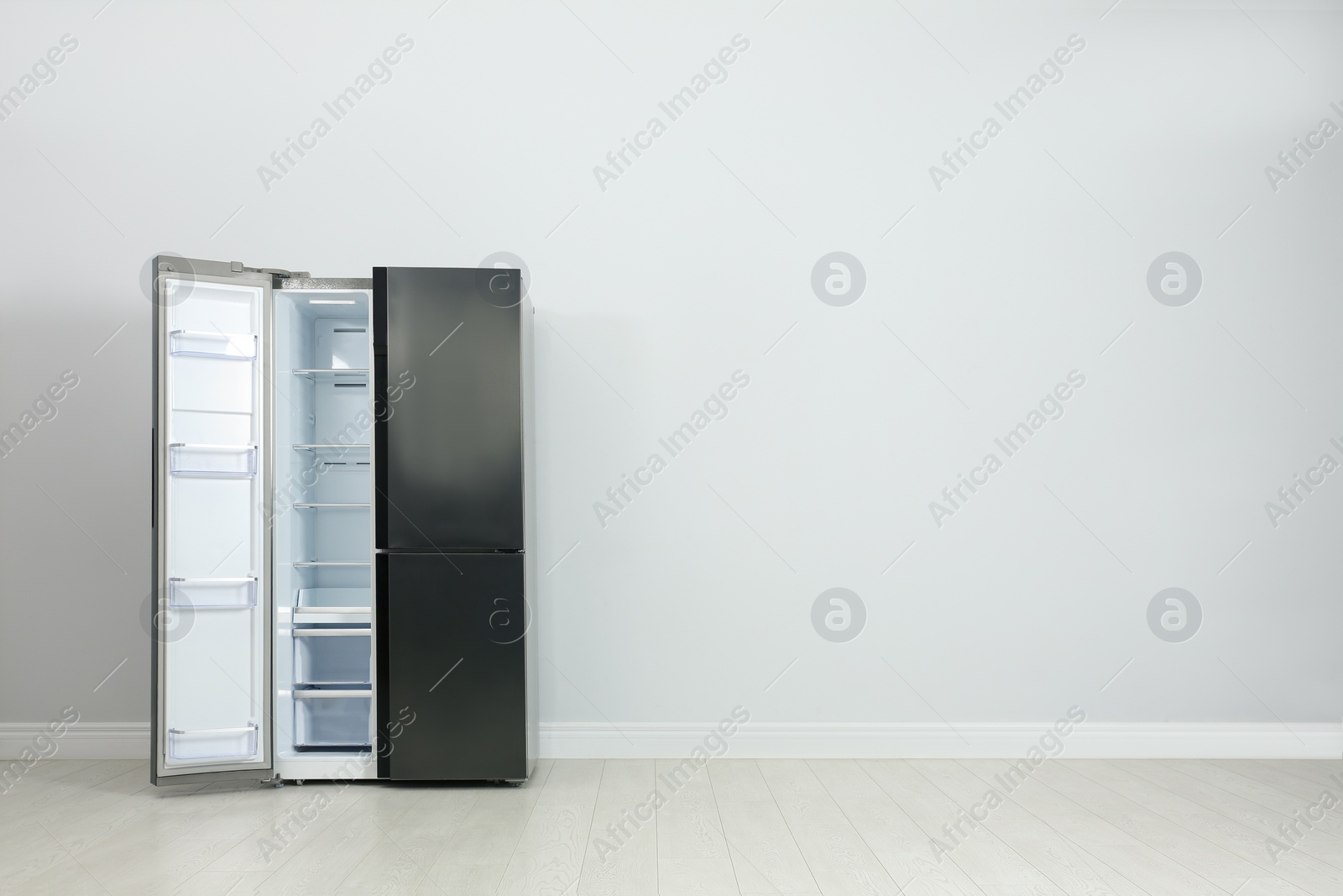 Photo of Modern refrigerator near light grey wall. space for text