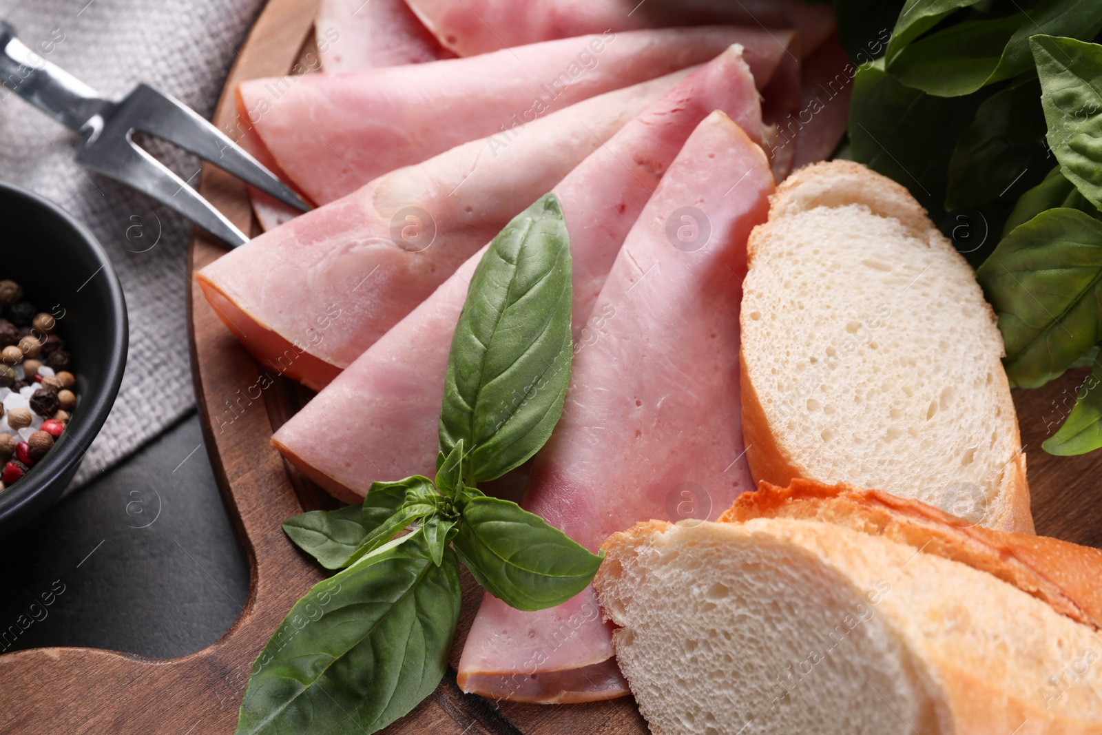 Photo of Tasty ham with basil, bread and carving fork on table, flat lay