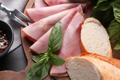 Tasty ham with basil, bread and carving fork on table, flat lay