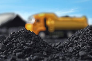 Image of Piles of coal and blurred yellow truck on background, closeup