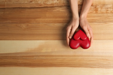 Photo of Woman holding decorative hearts on wooden background, top view. Space for text