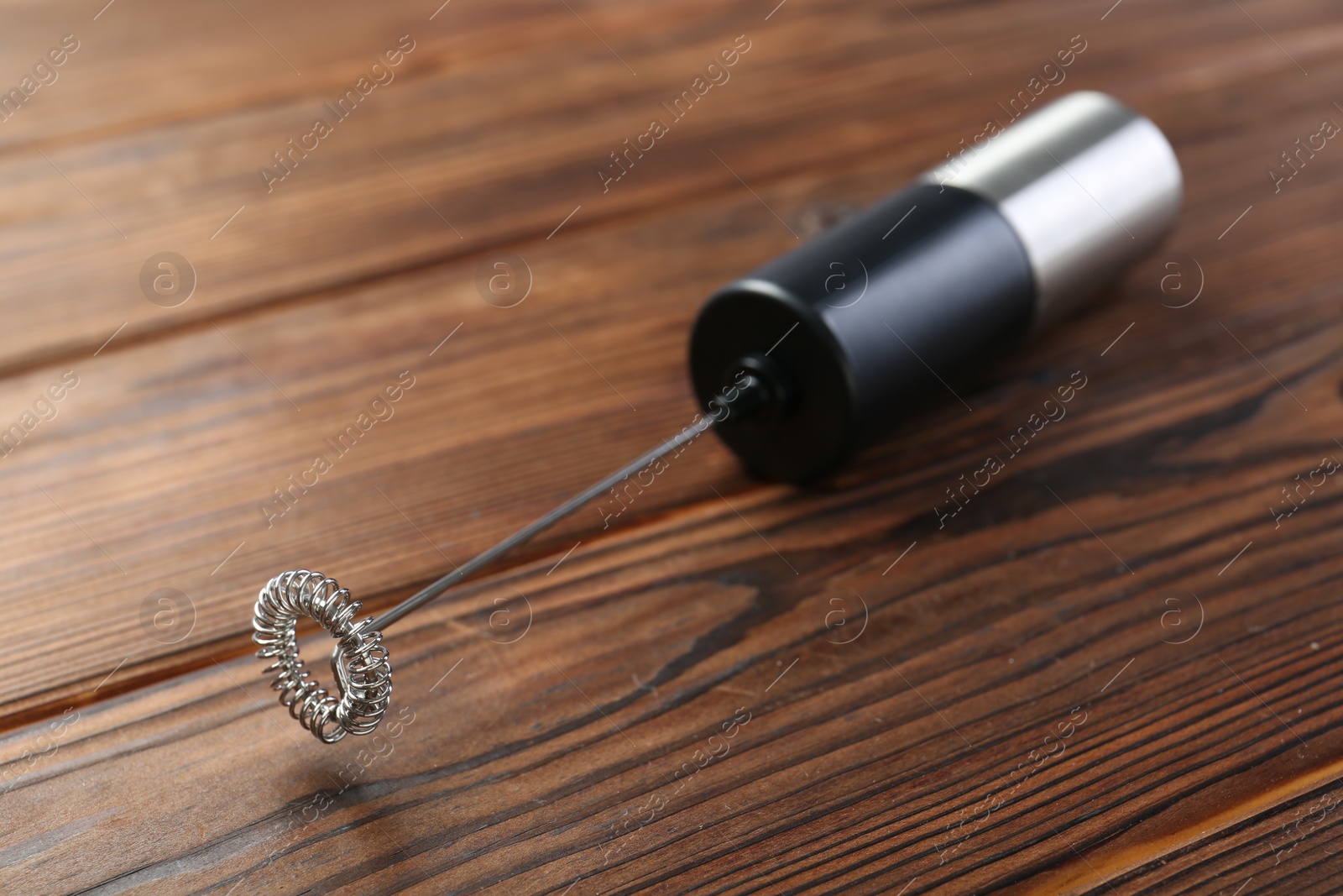 Photo of Black milk frother wand on wooden table, closeup