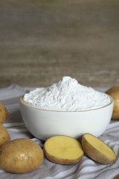 Photo of Starch and fresh raw potatoes on wooden table. Space for text