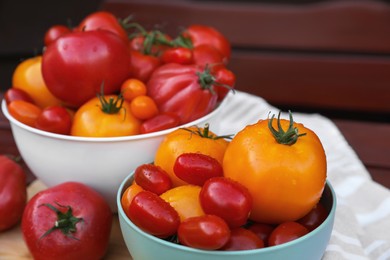 Photo of Bowls with fresh tomatoes on wooden surface, closeup
