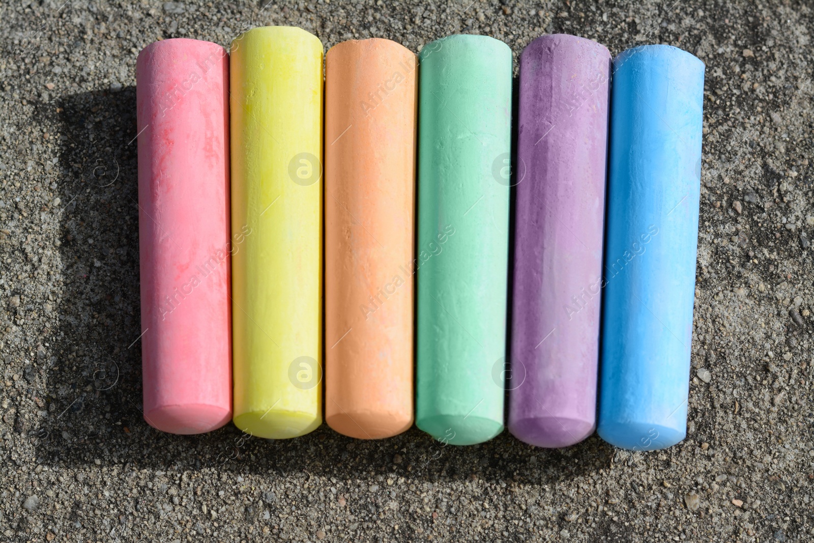 Photo of Colorful chalk sticks on asphalt, flat lay