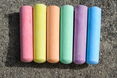 Colorful chalk sticks on asphalt, flat lay