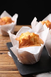 Photo of Delicious sweet muffins on wooden table against dark background, closeup