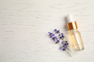 Flat lay composition with essential oil and lavender flowers on white wooden background. Space for text