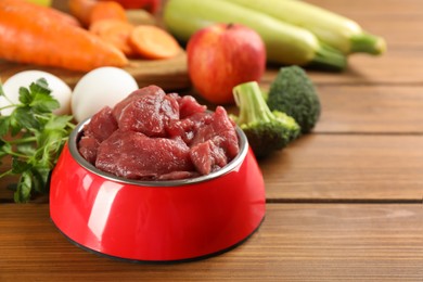 Photo of Raw meat and fresh ingredients on wooden table, closeup. Natural pet food