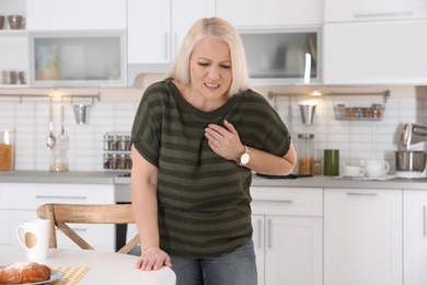 Mature woman having heart attack in kitchen