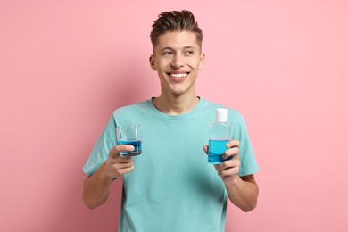 Young man with mouthwash on pink background