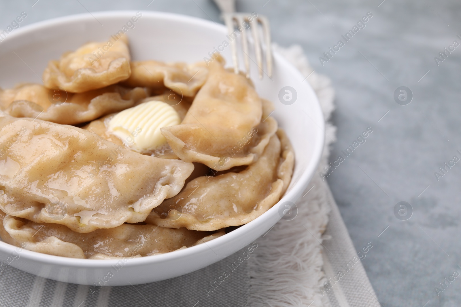 Photo of Delicious dumplings (varenyky) with cottage cheese and butter served on light grey table, closeup