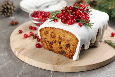 Traditional classic Christmas cake decorated with cranberries, pomegranate seeds and rosemary on table