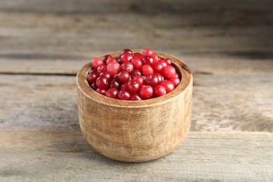 Photo of Ripe cranberries in bowl on wooden table