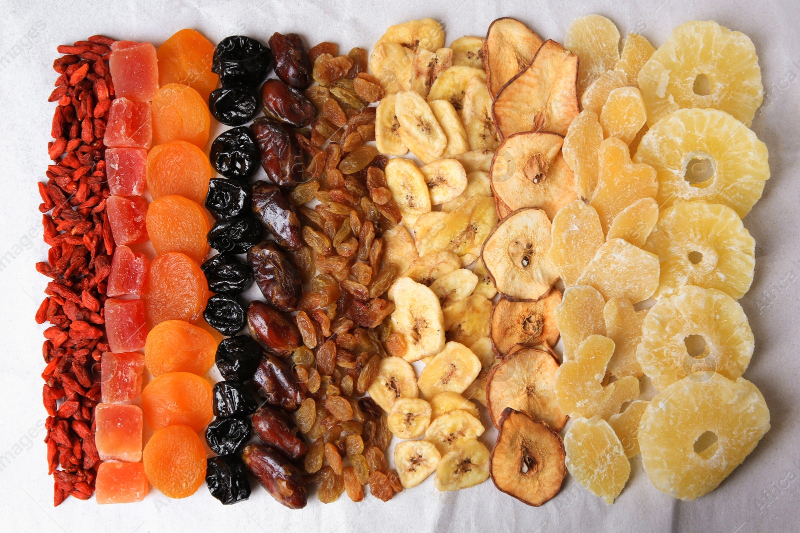 Photo of Different tasty dried fruits on paper, flat lay