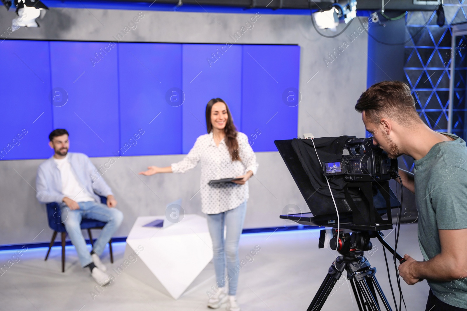 Photo of Presenters and video camera operator working in studio. News broadcasting