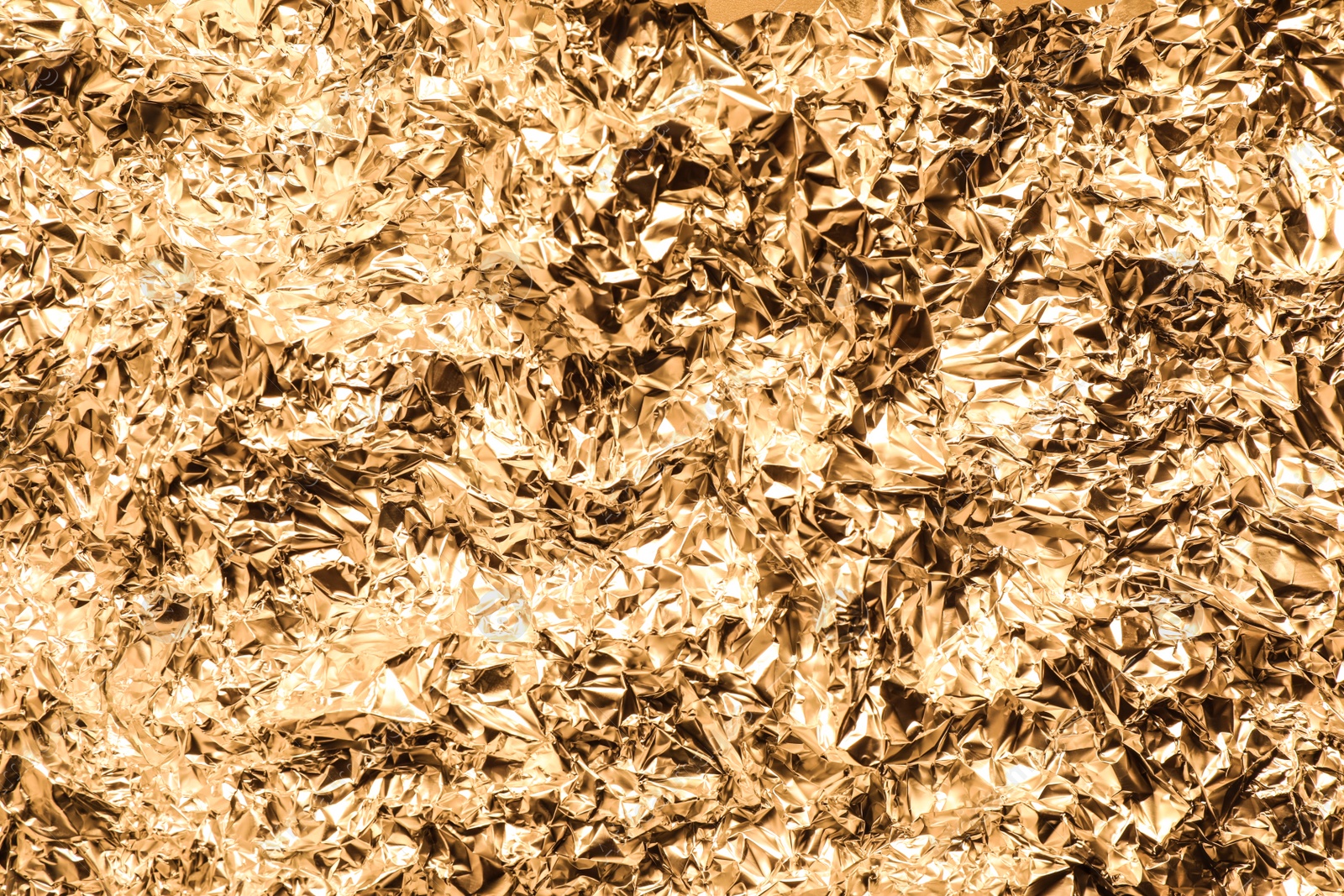 Photo of Crumpled gold foil as background, top view