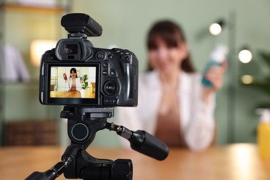Beauty blogger recording video while talking about cosmetic products at home, focus on camera