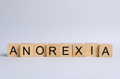 Photo of Word Anorexia made of wooden cubes with letters on light background