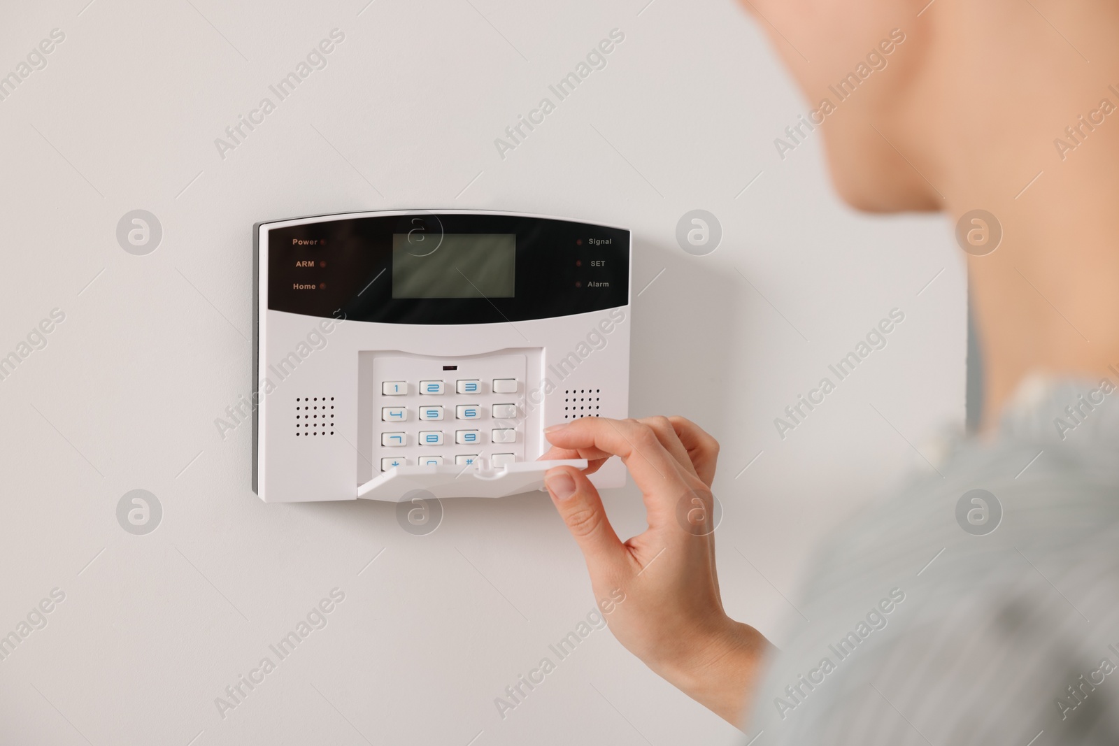 Photo of Woman entering code on security system, closeup