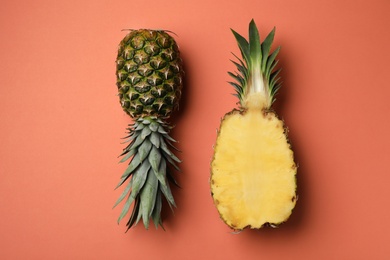 Photo of Fresh whole and cut pineapples on orange background, top view