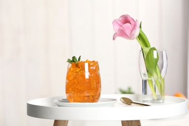 Photo of Glass of jelly and flower on table against blurred background