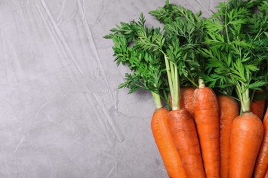 Photo of Bunch of fresh carrots on stone background, top view. Space for text