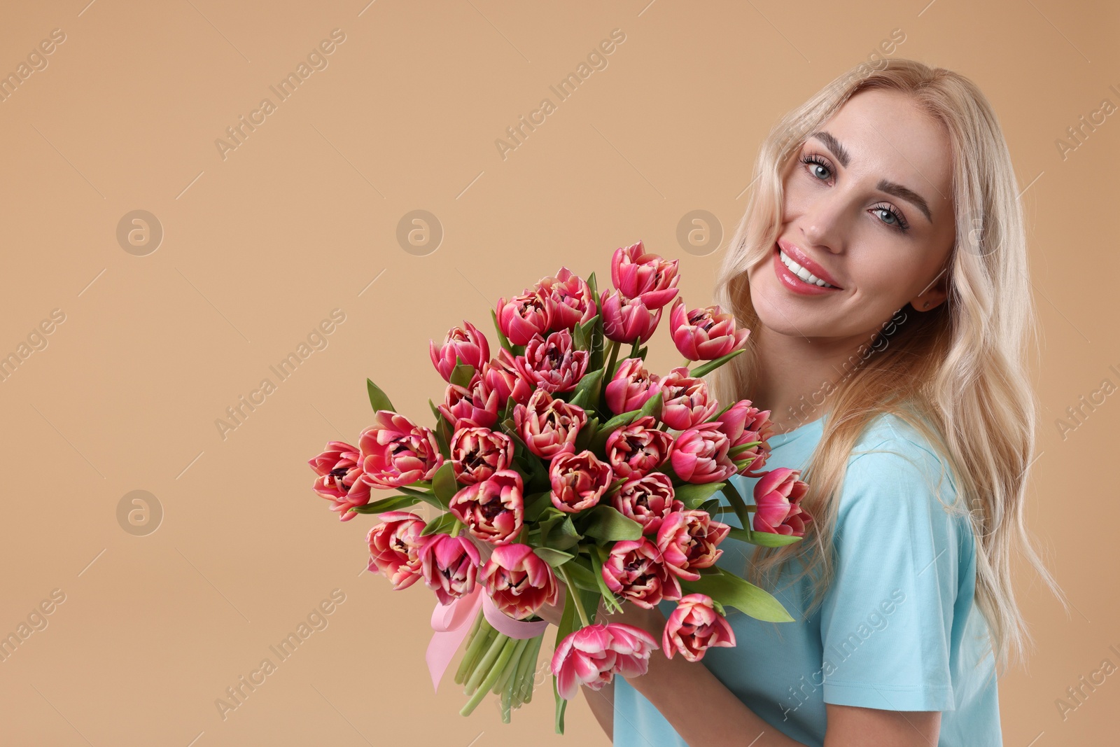 Photo of Happy young woman with beautiful bouquet on beige background. Space for text