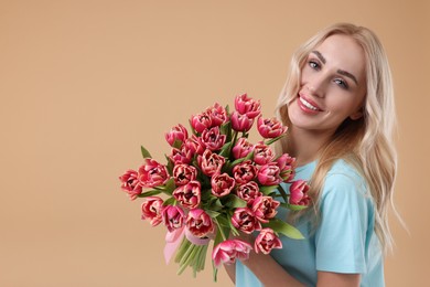 Happy young woman with beautiful bouquet on beige background. Space for text