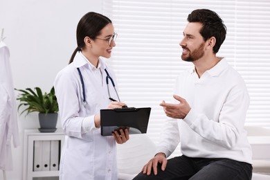 Doctor with clipboard consulting patient during appointment in clinic