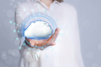 Image of Young woman holding cloud against grey background, focus on hand. Modern technology