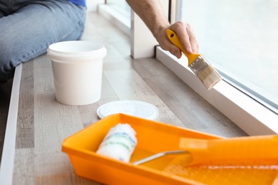 Photo of Man painting window frame at home, closeup