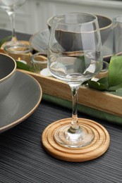 Place setting with glass and drink coaster on black wooden table, closeup view