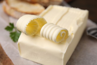 Photo of Tasty butter with curls on wooden board, closeup