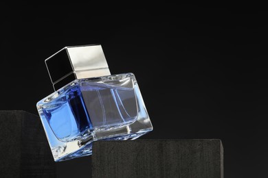 Photo of Luxury men`s perfume in bottle against dark background, space for text