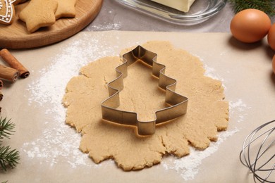 Photo of Making Christmas cookies. Raw dough and metal cutter on table