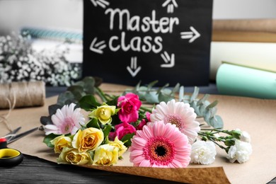 Photo of Flower arrangement master class. Paper wrapping with flowers on table, closeup