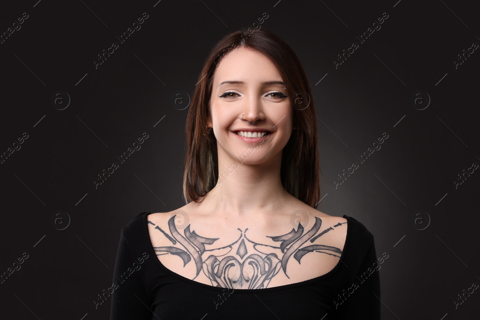 Photo of Portrait of smiling tattooed woman on black background