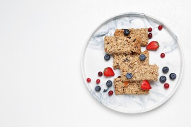 Photo of Tasty granola bars and berries on white background, top view. Space for text