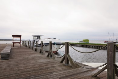Photo of Wooden pier with moored boat near sea. Real estate