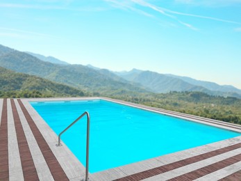 Image of Outdoor swimming pool at luxury resort with beautiful view of mountains on sunny day