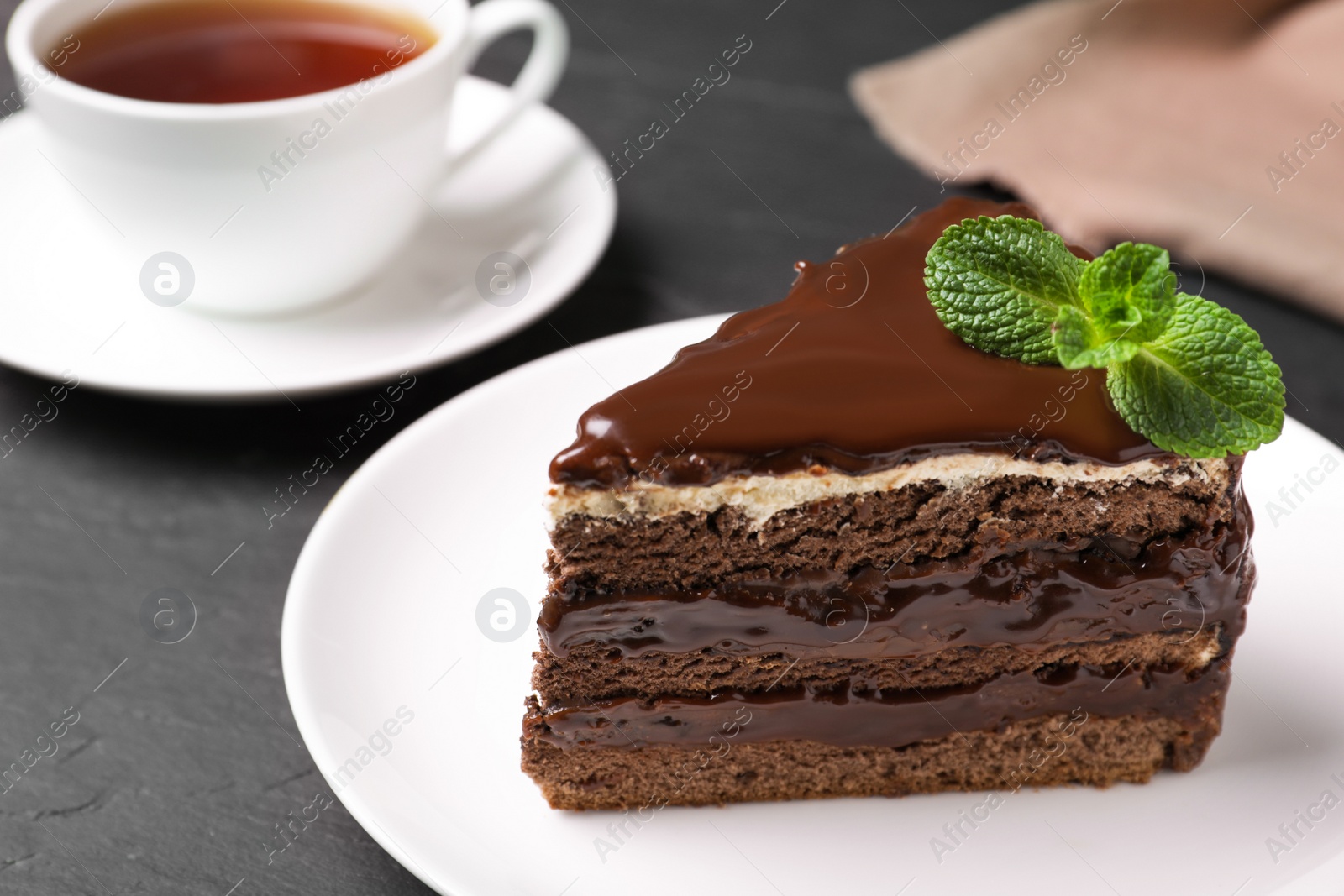 Photo of Delicious chocolate cake with mint on black table, closeup